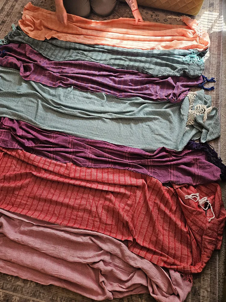 A row of colourful rebozo scarves laid side by side