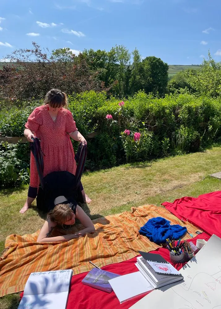 Rebozo massage being given on blankets in a sunny garden