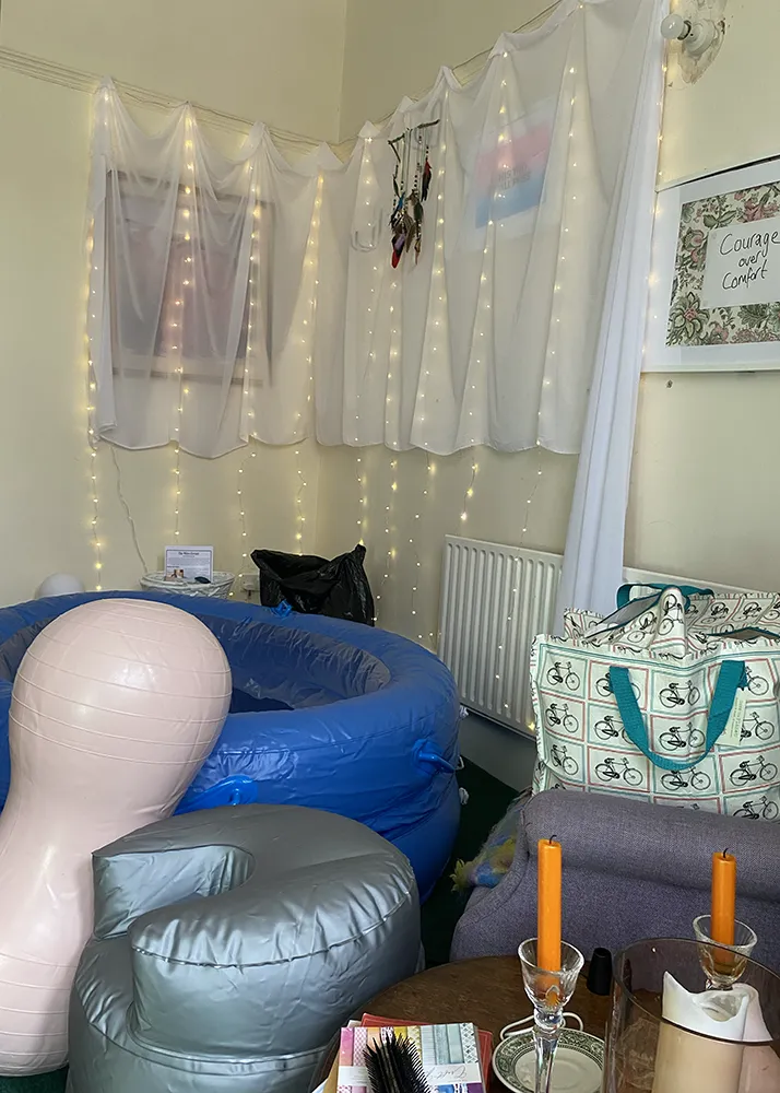 A birth pool set up with a peanut ball, an inflatable birth stool, fairy lights and candles
